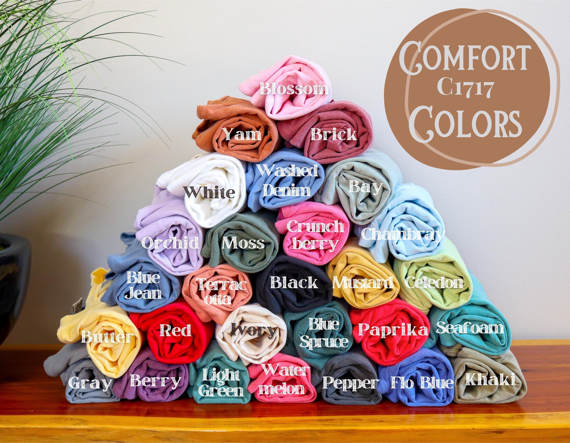 Stack of folded fabric swatches in various colors with labeled names on a wooden surface.