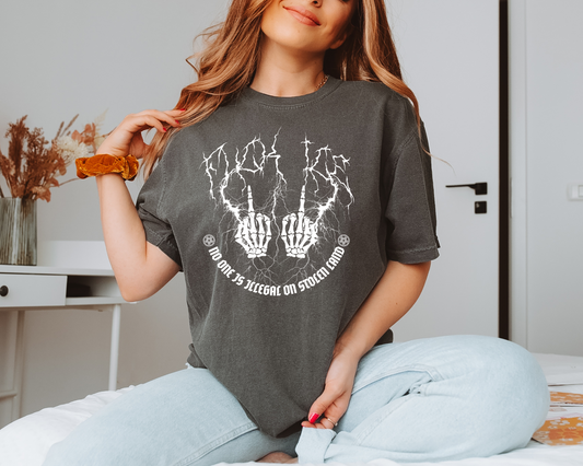 Woman wearing a dark gray t-shirt with a graphic design, sitting on a bed.